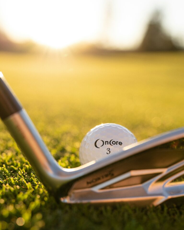 Golf ball and club at sunset moments before the swing – premium golf tour atmosphere with championship inspiration